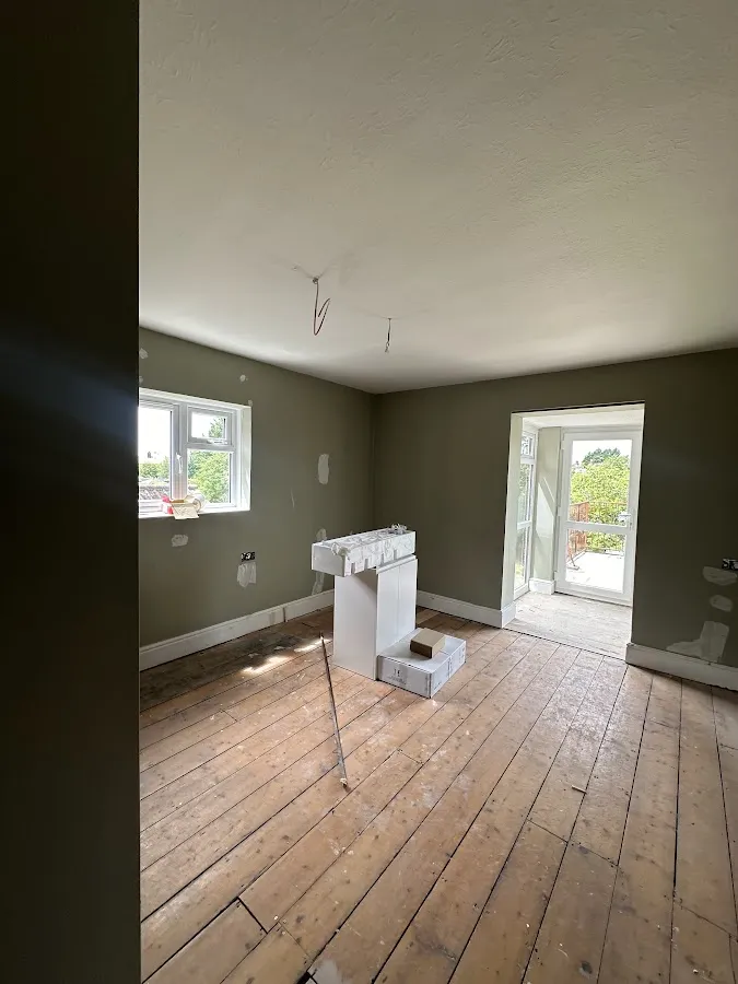 An empty room with bare floorboards before the work started