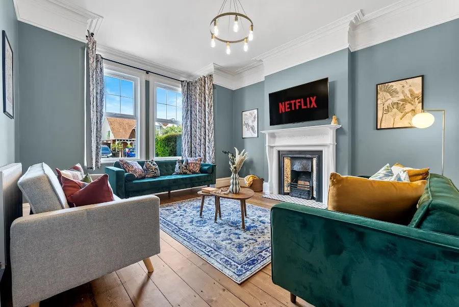 Living room with green velvet sofas, a fireplace and a blue patterned rug