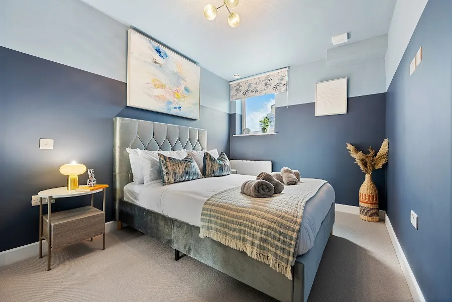 Bedroom with a navy feature wall and a grey upholstered bed