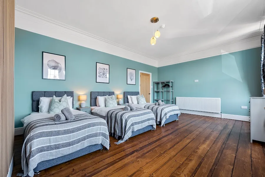 Triple bedroom with a blue wall and wooden floorboards